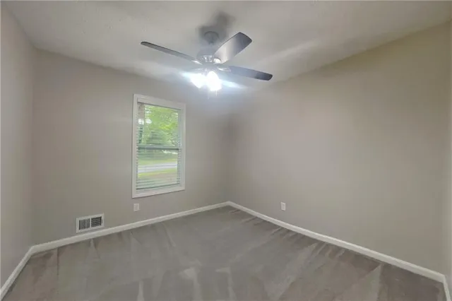 a view of an empty room with chandelier fan
