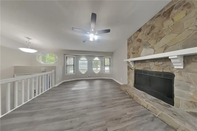 an empty room with wooden floor fireplace and windows