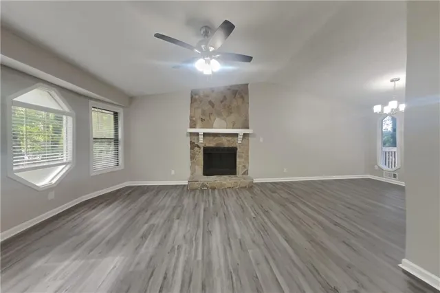 a view of an empty room with wooden floor fireplace and a window