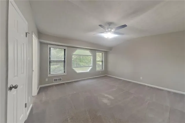 an empty room with a ceiling fan and window