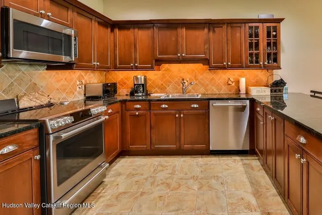a kitchen with stainless steel appliances granite countertop a stove a sink and a microwave