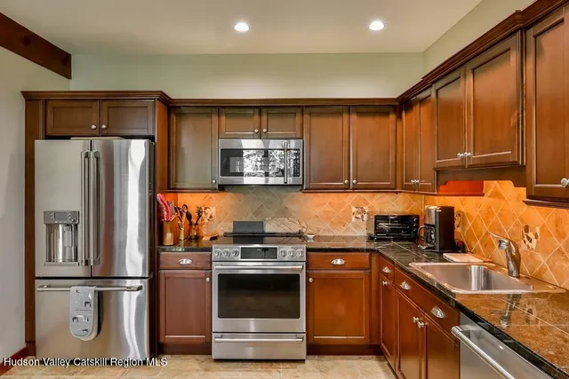 a kitchen with stainless steel appliances granite countertop a refrigerator sink and stove