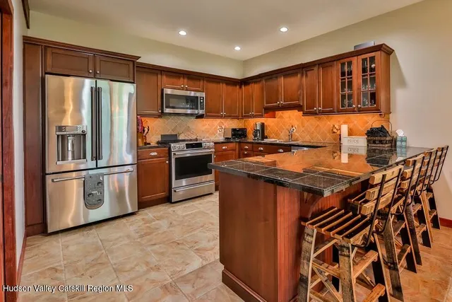 a kitchen with stainless steel appliances granite countertop a stove top oven a sink and a refrigerator