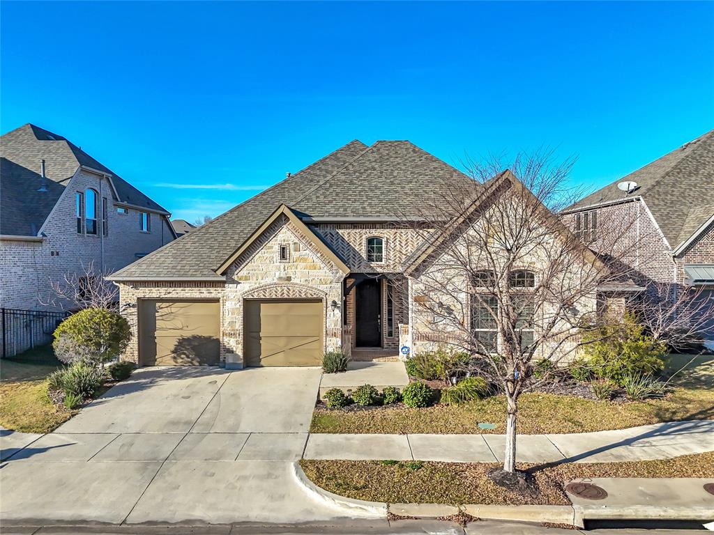 1011 Prairie Ridge Lane Arlington, TX 76005 - Photo 1 of 32 Brick and stone exterior featuring a gabled roofline, arched entry, two-car garage, and mature landscaping