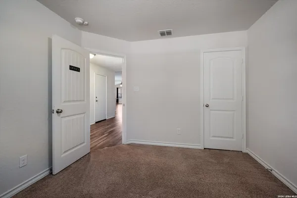 a view of an empty room with closet and a bathroom