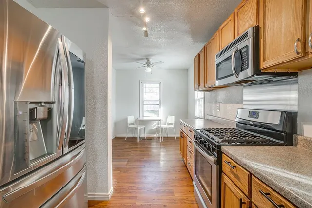 a kitchen with stainless steel appliances granite countertop a stove top oven a sink dishwasher and cabinets with wooden floor