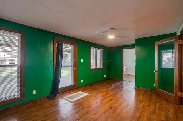 a view of an empty room with window and hardwood