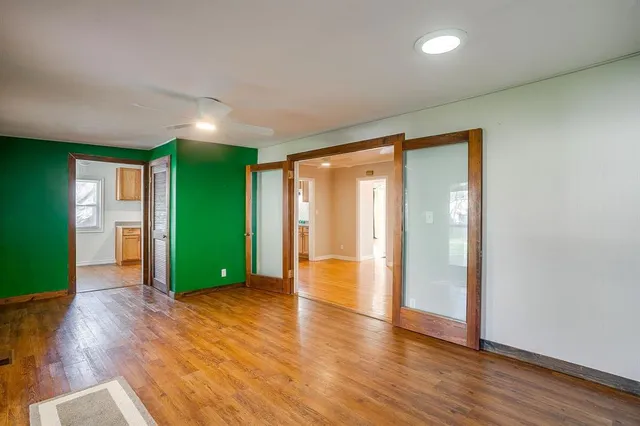 a view of an empty room with wooden floor and a window