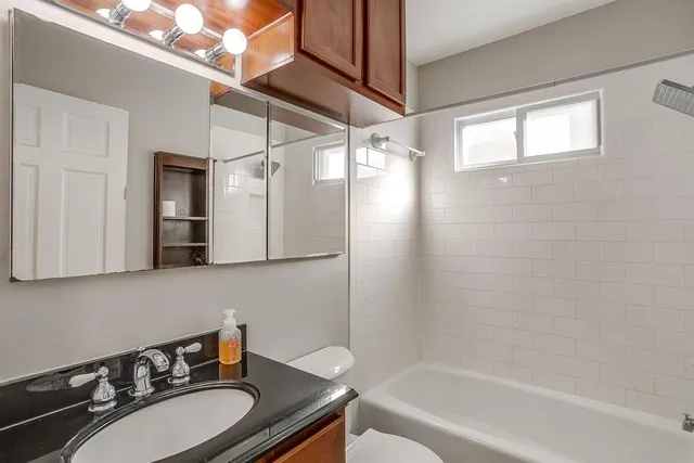 a bathroom with a granite countertop sink mirror toilet and bathtub