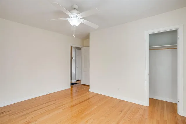 an empty room with wooden floor and fan