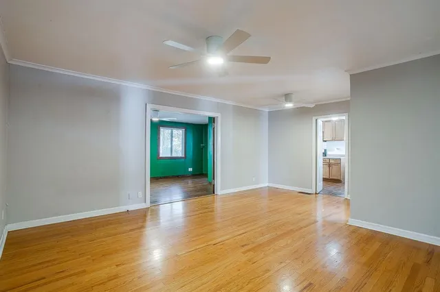 a view of an empty room with wooden floor and a window