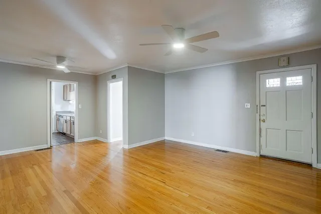 a view of an empty room with wooden floor and closet area