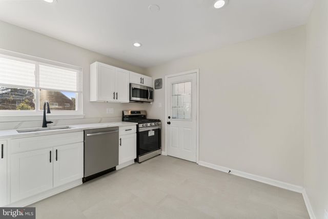 a kitchen with stainless steel appliances a sink a stove a refrigerator and cabinets