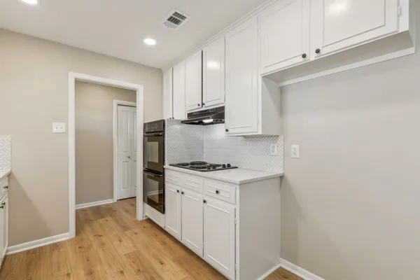 a kitchen with white cabinets and appliances