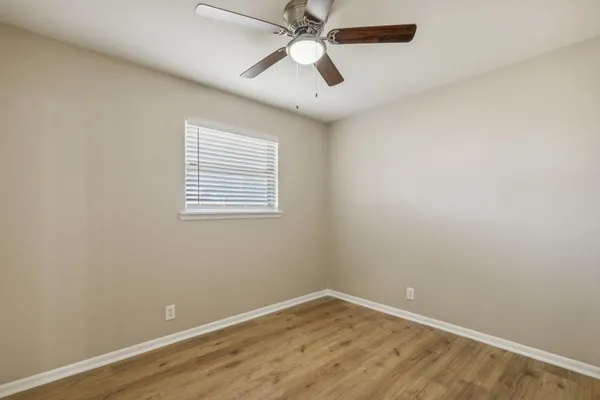 an empty room with a window and a fan