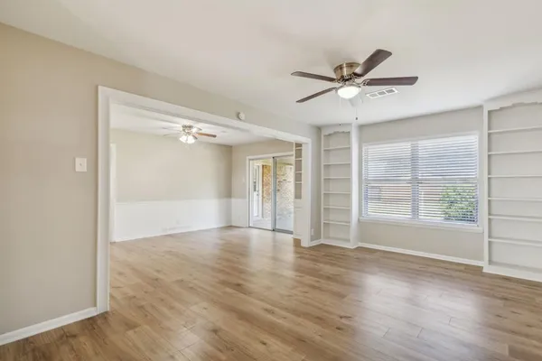 a view of an empty room with a window and wooden floor