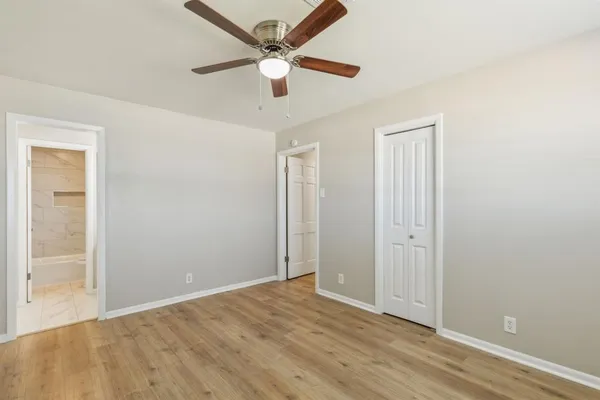 an empty room with wooden floor and a ceiling fan