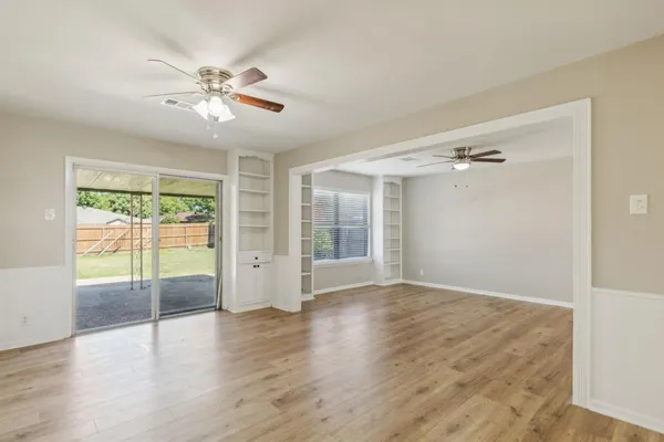 a view of an empty room with a window and wooden floor
