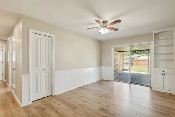 an empty room with wooden floor fan and windows