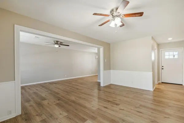 a view of a room with wooden floor and a ceiling fan