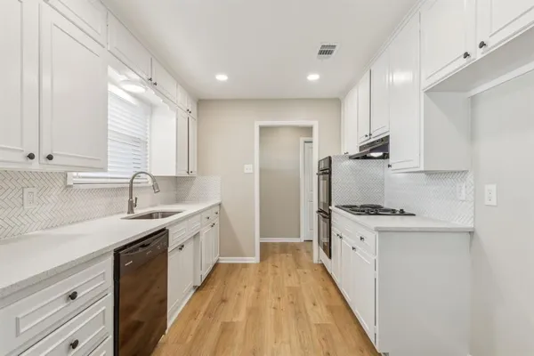 a kitchen with granite countertop a sink a counter top space stainless steel appliances and cabinets