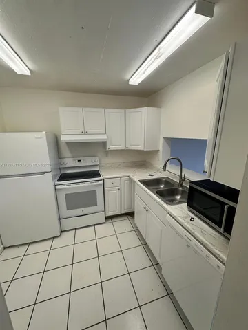 a kitchen with cabinets a sink and white appliances