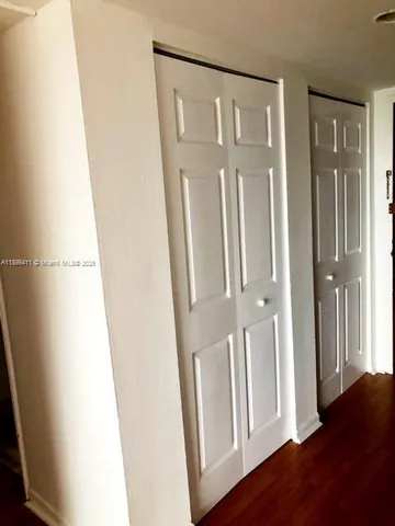 a view of a closet in a hall with wooden floor