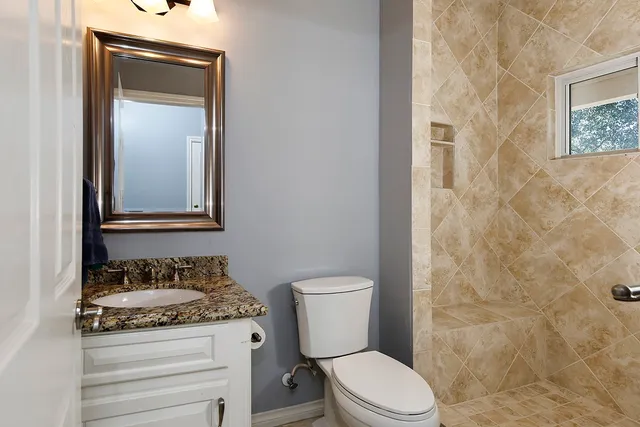 a bathroom with a granite countertop toilet and a sink