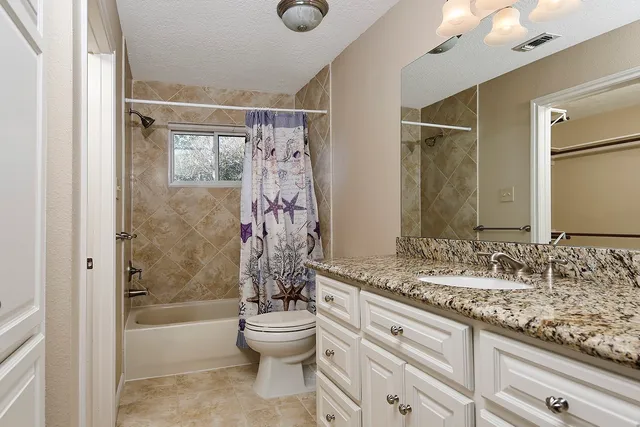 a bathroom with a granite countertop sink toilet and shower