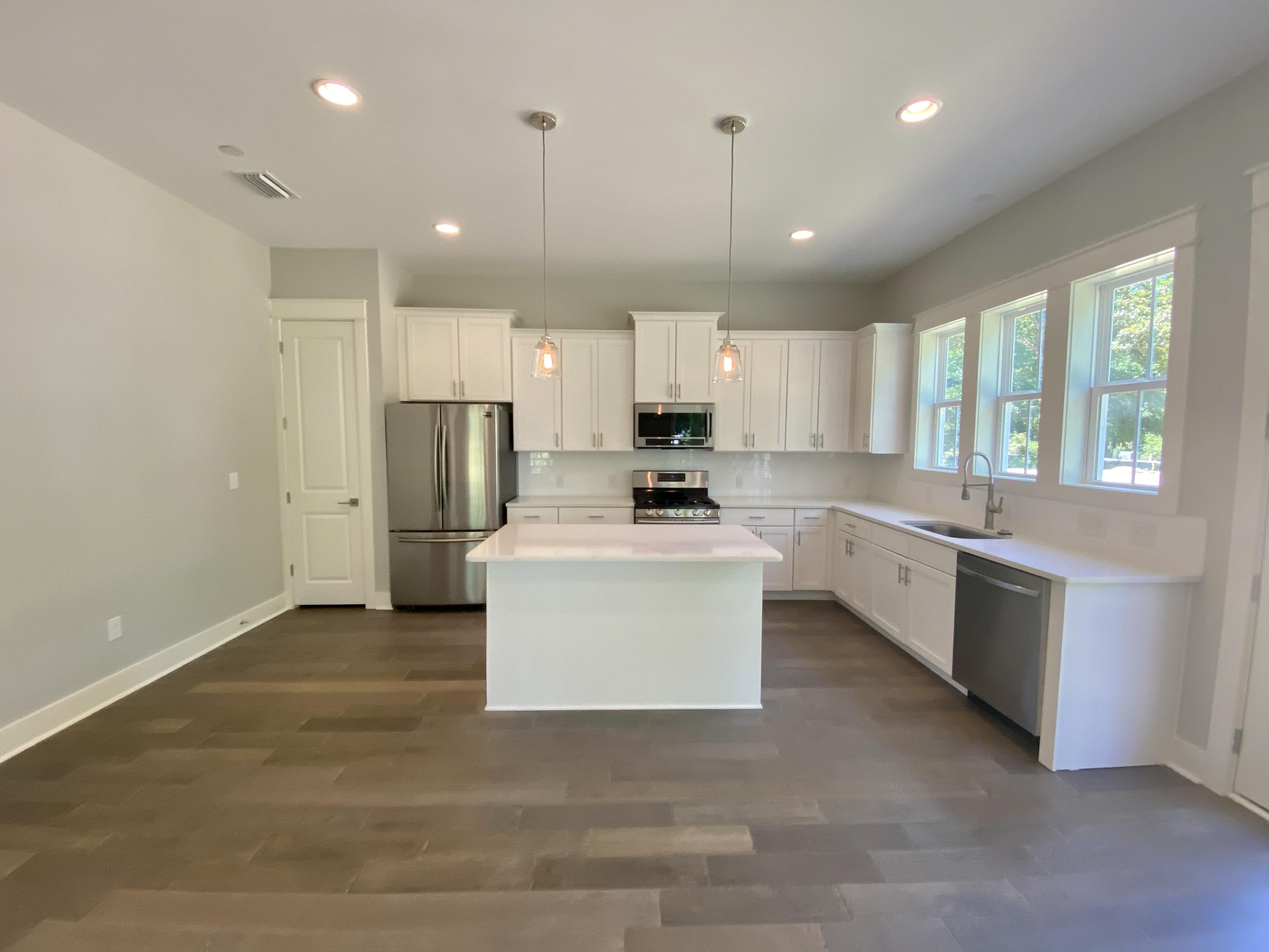103 Rearden Way Santa Rosa Beach, FL 32459 - Photo 5 of 31 a large white kitchen with kitchen island a stove a sink a refrigerator and white cabinets with wooden floor