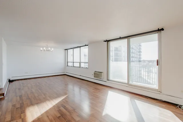 a view of an empty room with a window and wooden floor