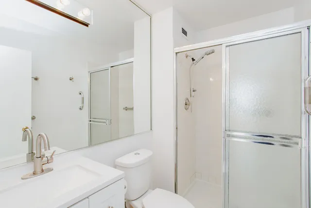 a bathroom with a shower sink vanity mirror and toilet