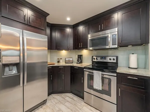 a kitchen with granite countertop kitchen island stainless steel appliances a sink and a refrigerator