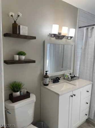 a bathroom with a granite countertop sink a toilet and a mirror