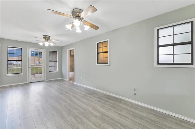 a view of an empty room with a window and wooden floor