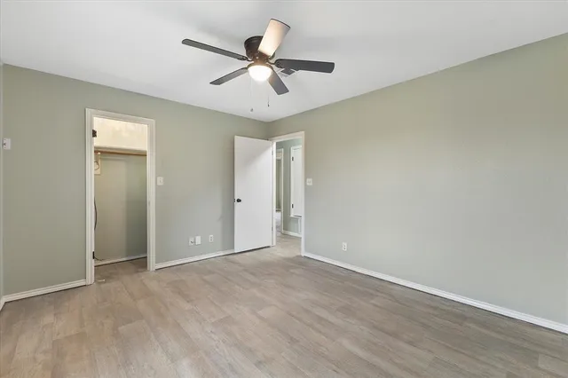 an empty room with wooden floor fan and windows