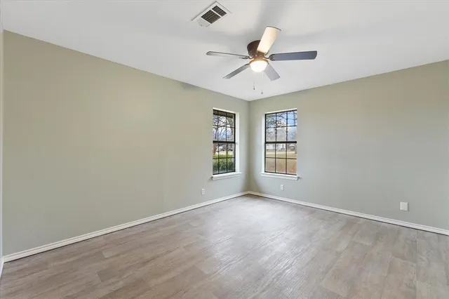 a view of an empty room with a window and wooden floor