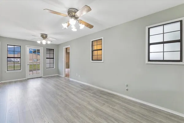 a view of an empty room with a window and wooden floor