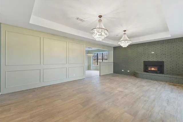 an empty room with a fireplace and chandelier