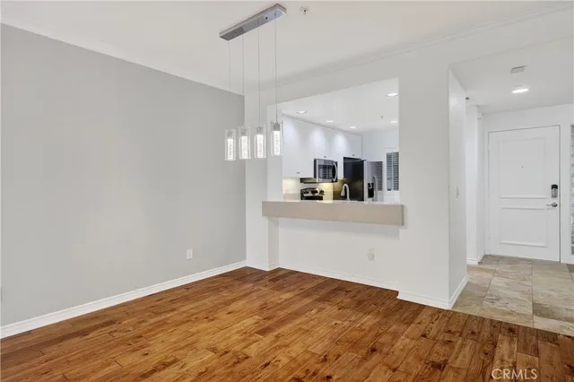 a view of kitchen and empty room with wooden floor