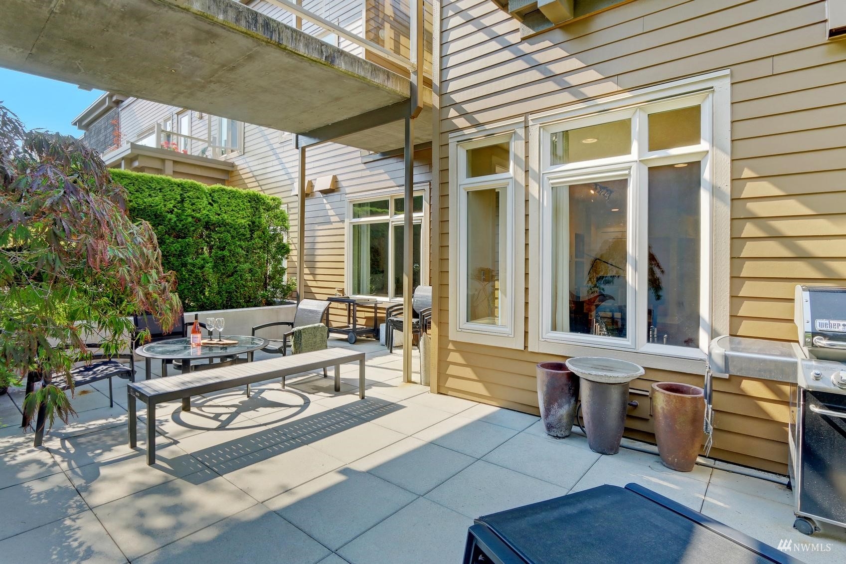 41 Pine Street, Unit 213 Edmonds, WA 98020 - Photo 20 of 25 a view of a patio with table and chairs potted plants and floor to ceiling window