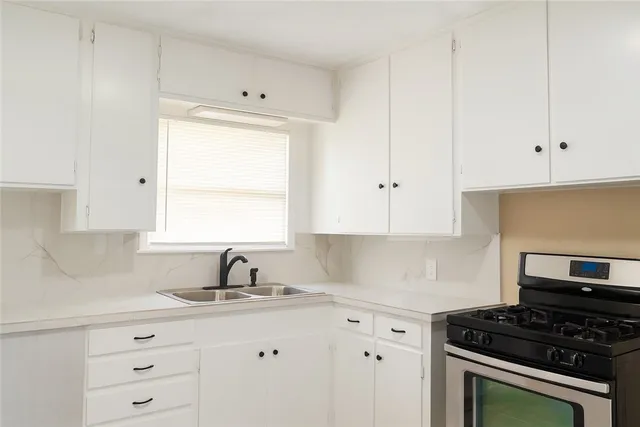 a kitchen with granite countertop white cabinets and window