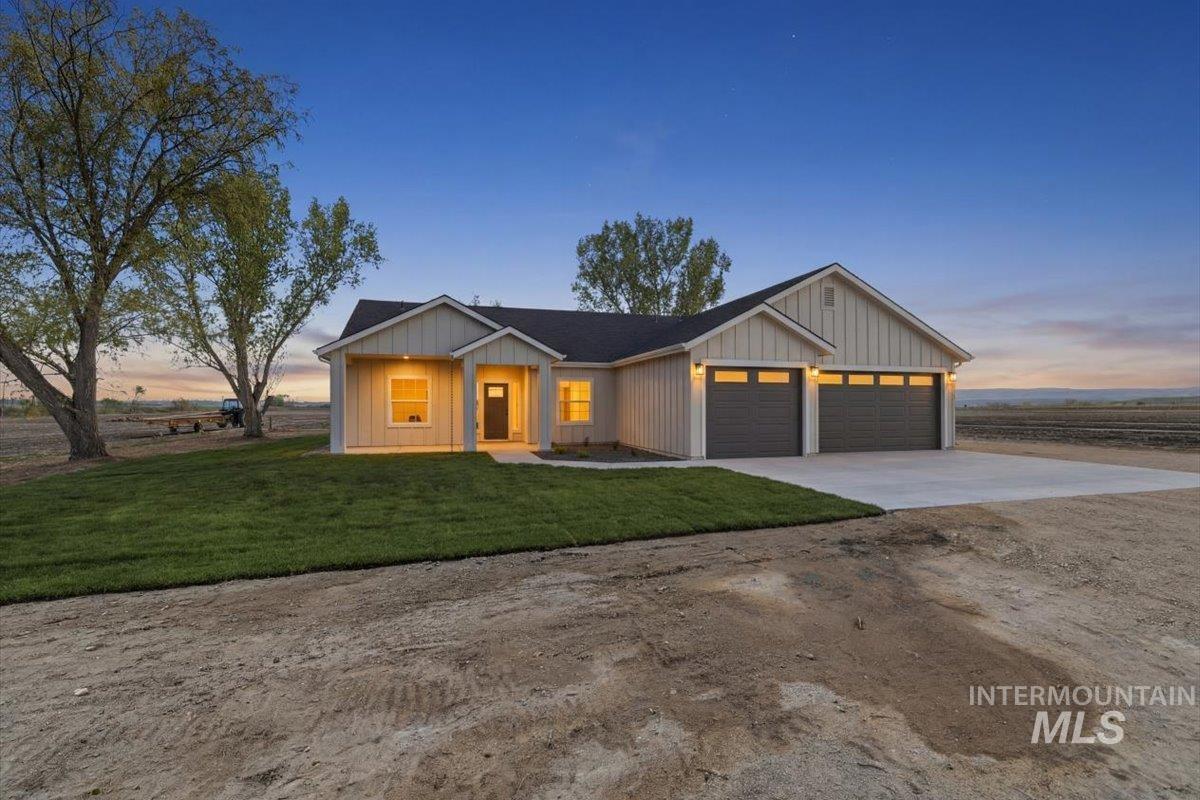 Modern inspired farmhouse with concrete driveway, an attached garage, a front yard, and board and batten siding