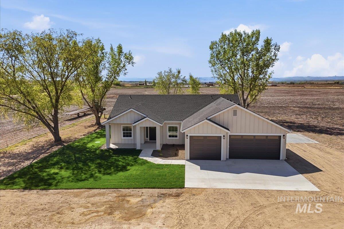 29343 Dixie Road Parma, ID 83660 - Photo 13 of 35 Modern farmhouse featuring concrete driveway, board and batten siding, a shingled roof, a garage, and a front yard
