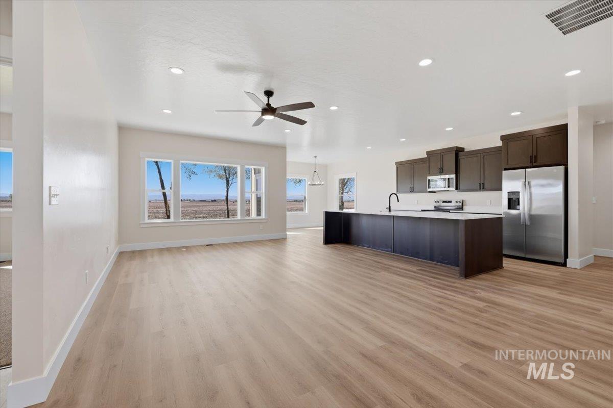 29343 Dixie Road Parma, ID 83660 - Photo 35 of 35 Kitchen featuring stainless steel appliances, dark wood finish cabinets, open floor plan, light countertops, and a center island with sink