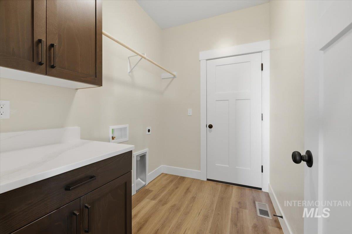 29343 Dixie Road Parma, ID 83660 - Photo 23 of 35 Laundry room with cabinet space, light wood-style floors, washer hookup, and hookup for an electric dryer