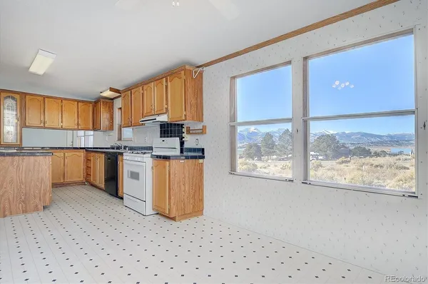 a kitchen with granite countertop a stove top oven a sink dishwasher and white cabinets with wooden floor