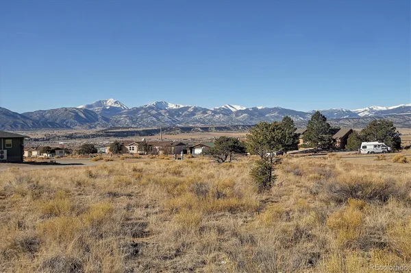 a view of a dry field with mountains in the background