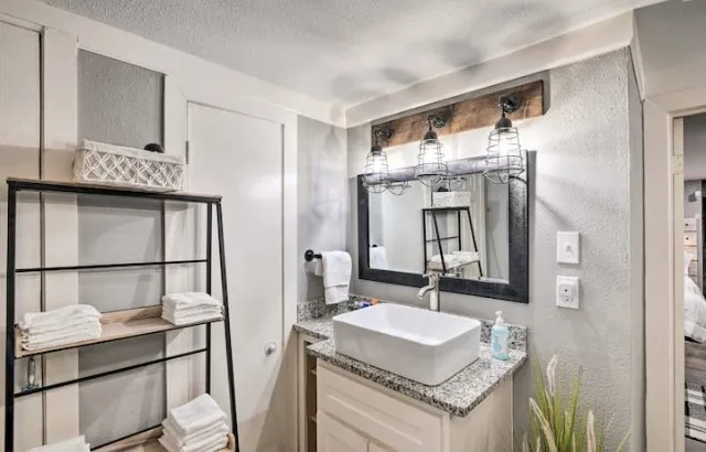 a bathroom with a granite countertop sink and a mirror