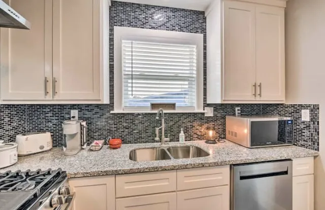a kitchen with granite countertop a sink stove and cabinets